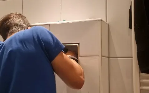 Monteur werkt via de bedieningsopening aan het toiletreservoir in Heerlen.
